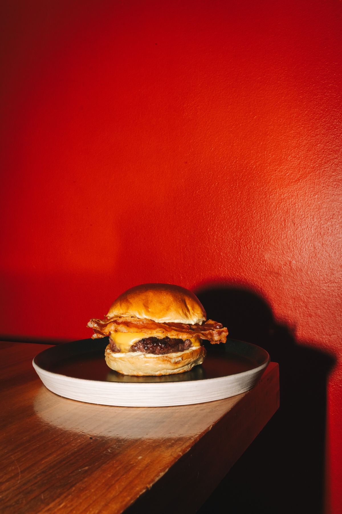 Hamburguesa con bacon y cheddar de La Real sobre fondo rojo